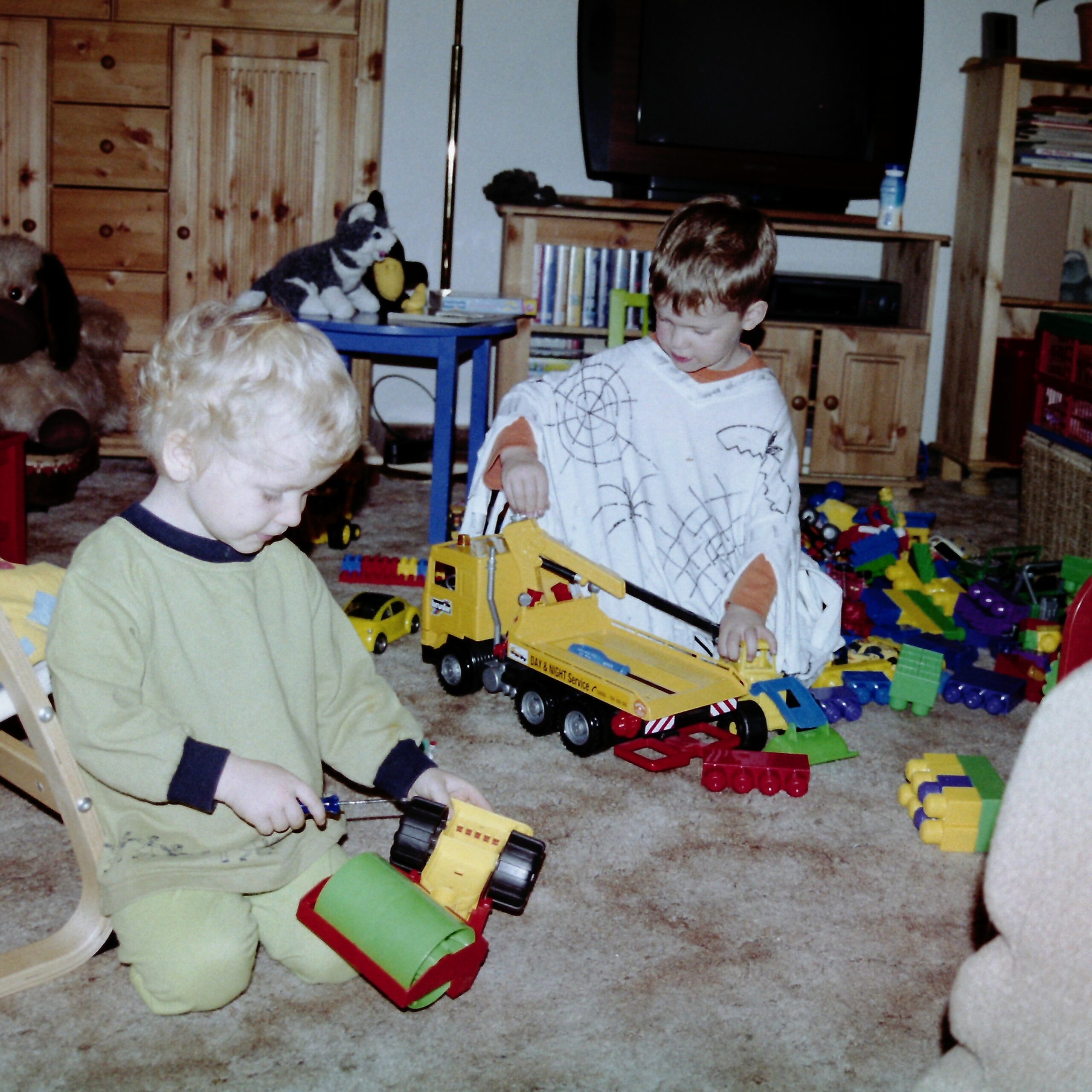 Zwei kleine Kinder spielen auf einem Teppich mit Spielzeugbaggern